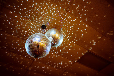 Low angle view of illuminated disco balls hanging from ceiling in nightclub