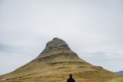 Rear view of man looking at mountain against sky