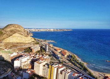 High angle view of cityscape by sea against clear sky