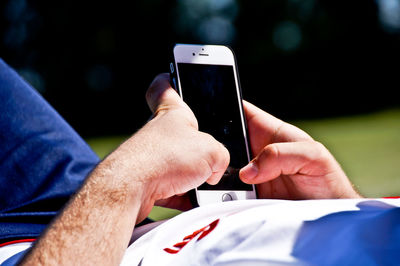 Midsection of man using mobile phone while lying on field