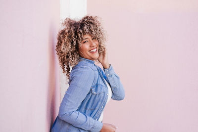 Portrait of young woman standing against wall