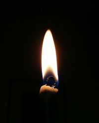 Close-up of lit candle in darkroom