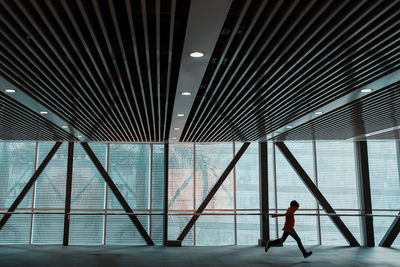 Side view of boy running on floor in building