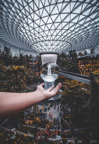 Person holding umbrella seen through glass ceiling