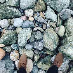 Low section of man standing on pebbles