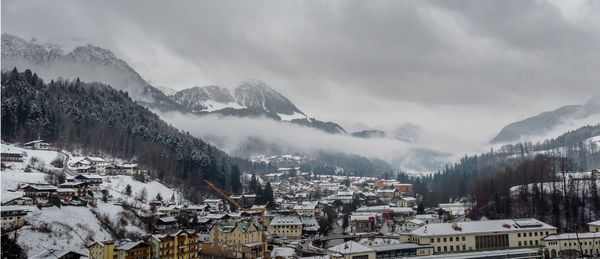 Panoramic view of buildings and snowcapped mountains against sky