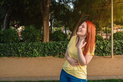 Young woman standing against trees