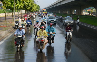 People riding bicycle on wet road in city during rainy season