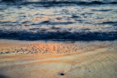 Surface level of beach against sky during sunset