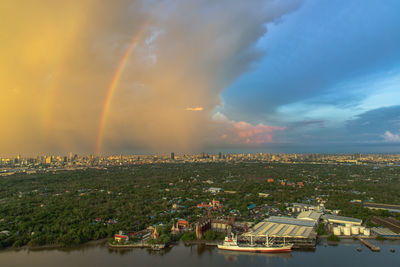 Panoramic view of rainbow over cityscape against sky