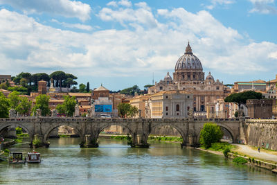 Arch bridge over river tiber against buildings in front of st. peter's basilica