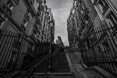 Low angle view of man standing on staircase amidst buildings in city