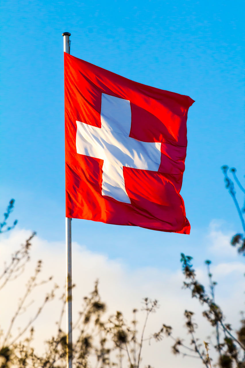 LOW ANGLE VIEW OF RED FLAG AGAINST BLUE SKY