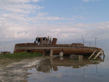 Abandoned boat in lake against sky