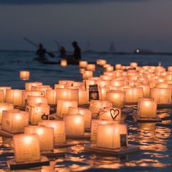 Close-up of illuminated candles on beach against sky during sunset