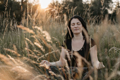 Woman meditating while sitting on grass