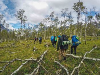 Rear view of people walking on field against sky