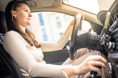 Side view of young woman using mobile phone while sitting in car