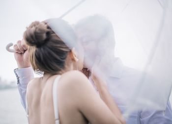 Rear view of woman kissing man under umbrella