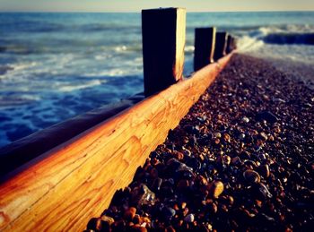 Close-up of wooden railing at beach against sky