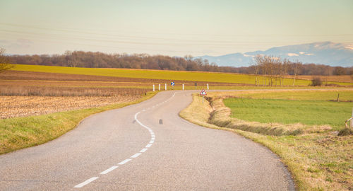 Road amidst field against sky