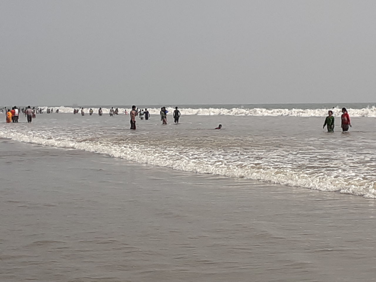 GROUP OF PEOPLE ON BEACH AGAINST CLEAR SKY