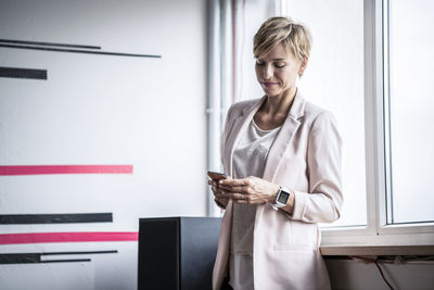 Businesswoman at the window looking at cell phone