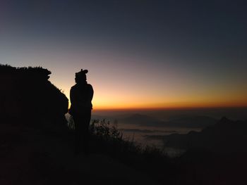 Silhouette man standing on mountain against sky during sunset