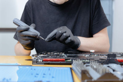 A young man repairs a computer at home.