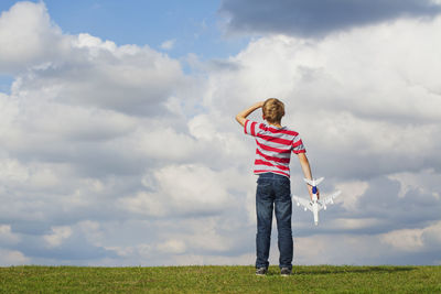 Full length of boy standing on field against sky