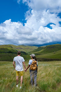 Rear view of woman standing on field against sky