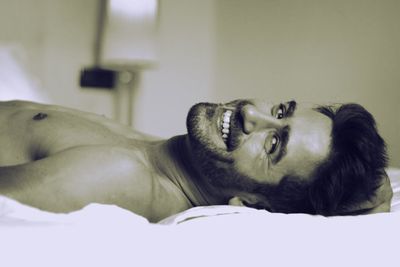 Portrait of smiling young man lying on bed at home