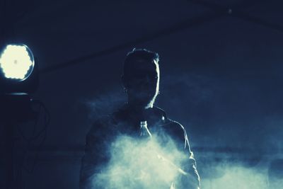 Man standing by smoke with bottle during concert