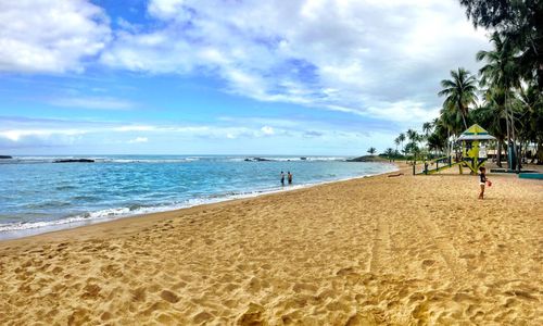 Scenic view of beach against cloudy sky