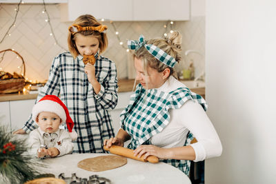 Happy family mother and children son and daughter bake cookies for christmas. christmas spirit