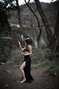 Full length of young woman wearing gas mask standing at forest