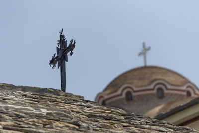 Low angle view of cross on roof against sky