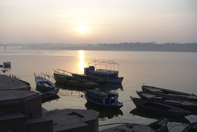 Boats moored in lake against sky during sunset