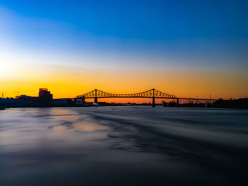 Bridge over sea against sky during sunset