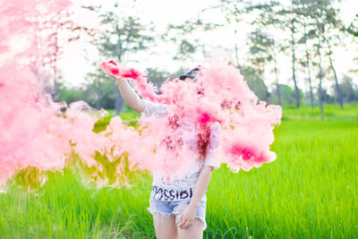 Woman with pink distress flare while standing on grass