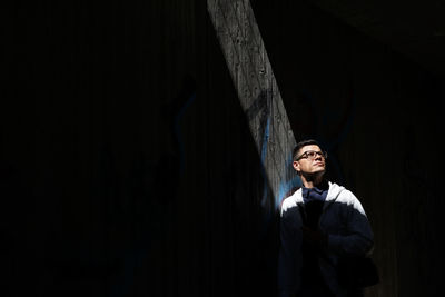 Sunlight falling on thoughtful man standing by wall