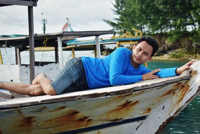 Portrait of young man lying on boat in sea