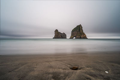 Rock formations on shore against sky