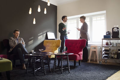 Businessman sitting while colleagues discussing in office