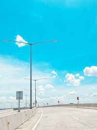 Street light by road against blue sky