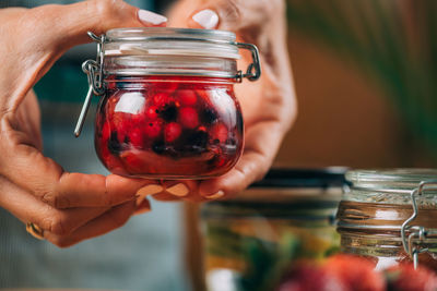 Woman holding jars with fermented fruits.