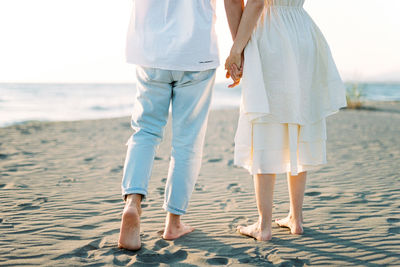 Low section of couple standing at beach