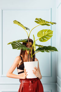 Stylish woman with potted plant in studio