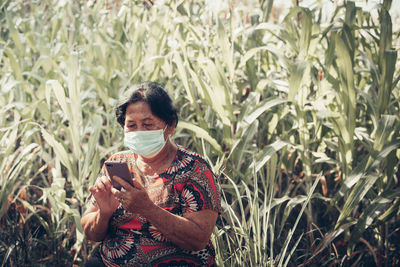 A woman holding smart phone while standing on field