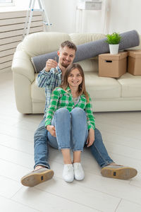 Portrait of couple sitting by sofa at home